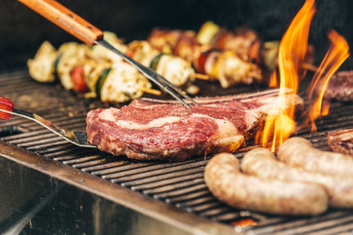 Steak, vegetable kabobs, and sausages on a flame topped grill, showing that even though keto is a diet, you can still pack up on delicious food.